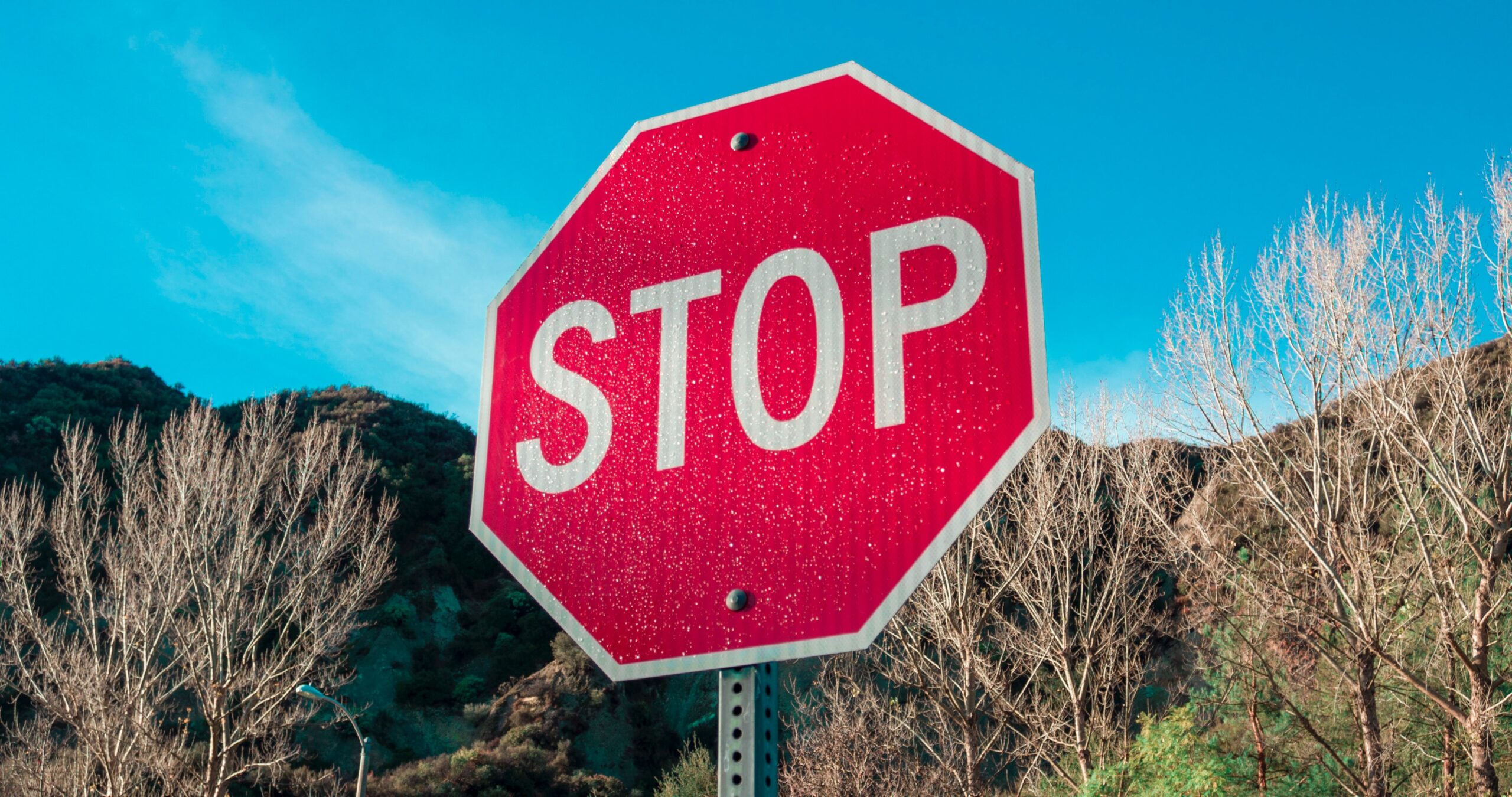 A big red stop sign set against a sunny blue sky.