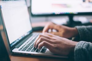 A person is writing using a laptop