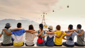 A row of people sit on a wall with arms around each other as a team